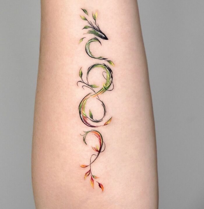 Abstract infinity tattoo on arm, featuring colorful leaves and intricate design elements.