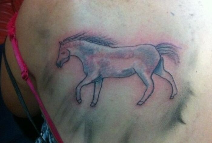Poorly drawn horse tattoo on a person's back, showcasing a tattoo fail with faded colors and awkward anatomy.