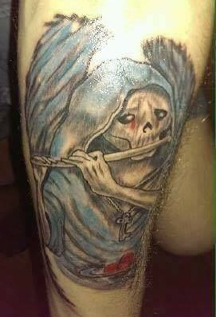 Grim reaper tattoo fail with uneven lines and colors on skin.