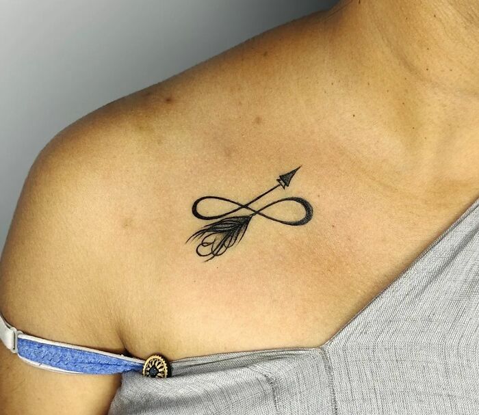 Infinity tattoo with arrow design on shoulder, symbolizing eternal creativity.