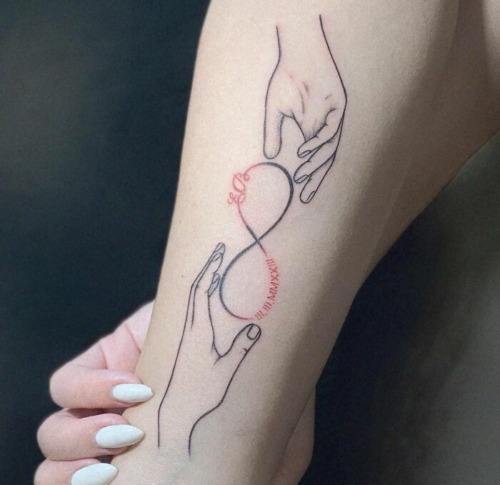 Infinity tattoo on an arm with two hands holding an infinity symbol, showcasing eternal creativity.