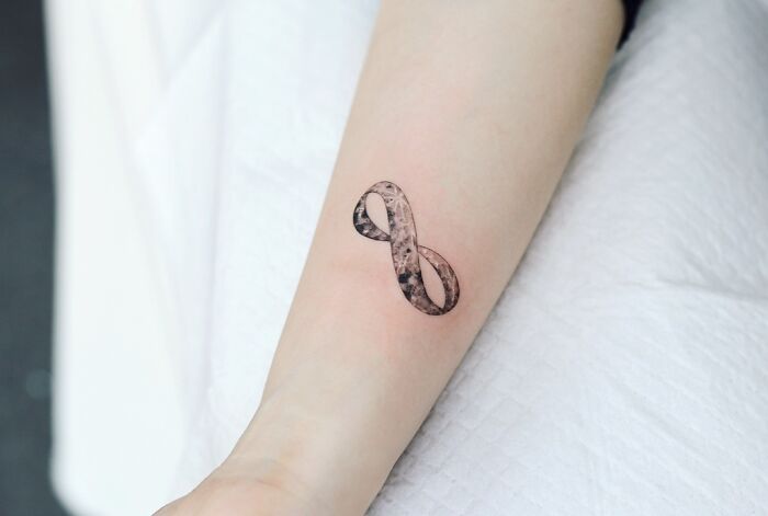Infinity tattoo design on forearm, showcasing eternal creativity with subtle shading.