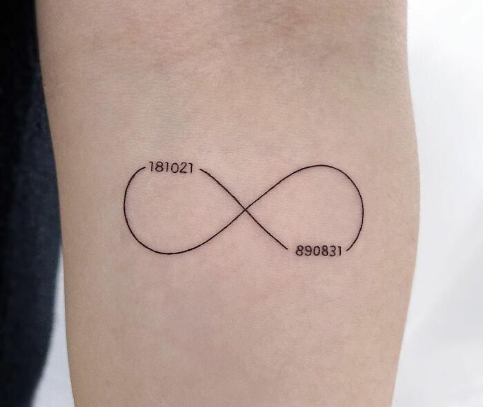 Infinity tattoo with numbers 181021 and 890831 on skin, symbolizing eternal creativity.