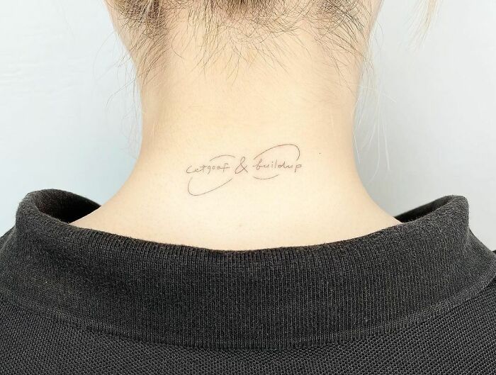 Small infinity tattoo with cursive script on the back of a neck, showcasing eternal creativity in minimalist design.