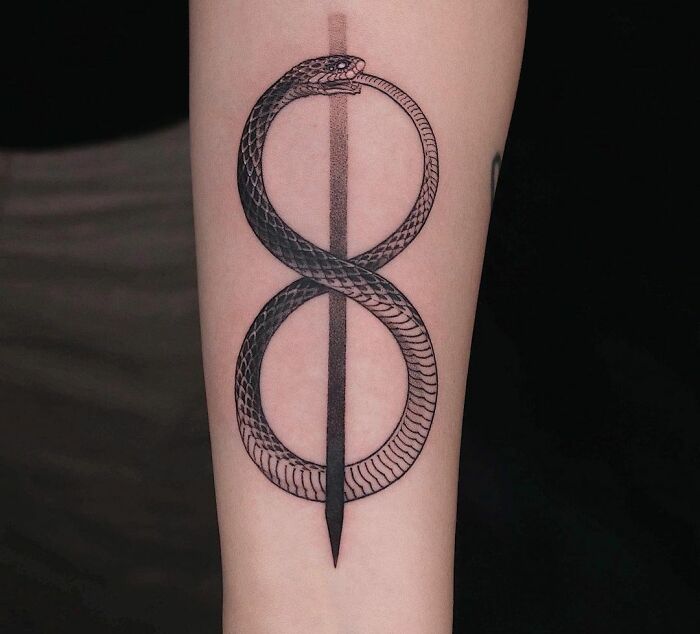 Infinity tattoo featuring a snake looped in the shape of an eight on a forearm.