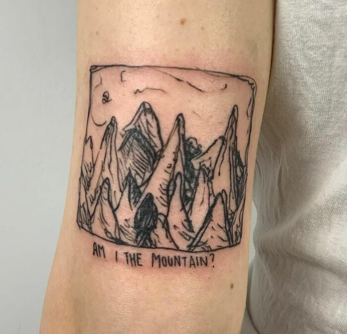 Abstract mountain tattoo with the phrase "Am I the Mountain?" showcasing artistry and self-expression.