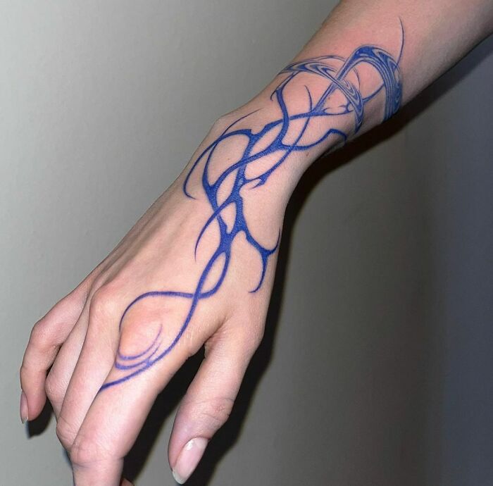 Abstract tattoo in blue ink on a wrist, showcasing artistry and self-expression.