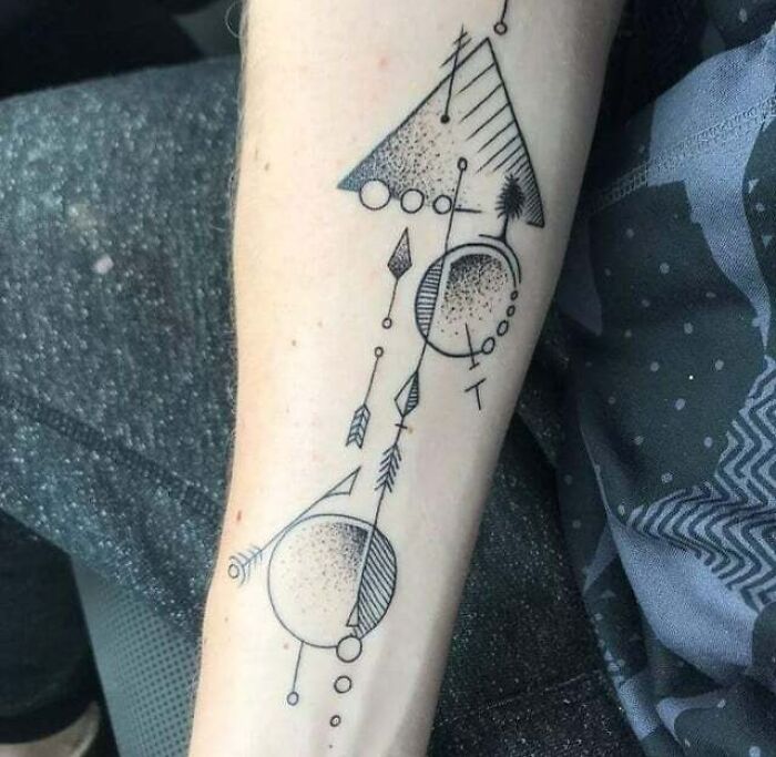 Abstract tattoo featuring geometric shapes and lines on a forearm.