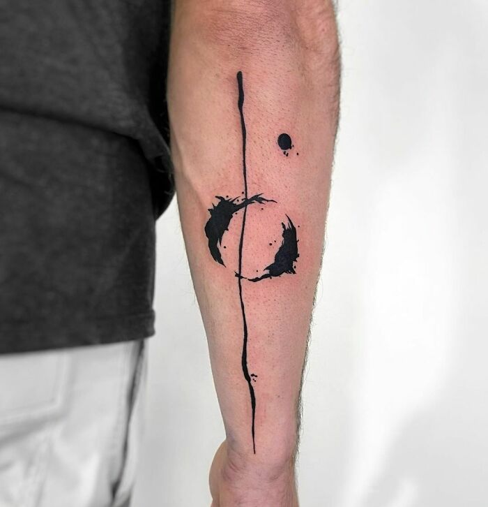 Abstract tattoo featuring bold black ink shapes on a forearm, exemplifying artistry and self-expression.