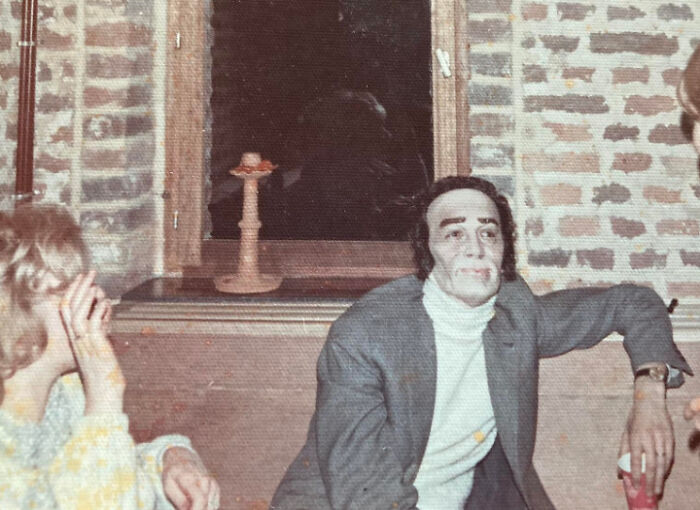 Vintage photo of two people sitting by a brick wall, showcasing one of the weirdest pics shared in an online group.