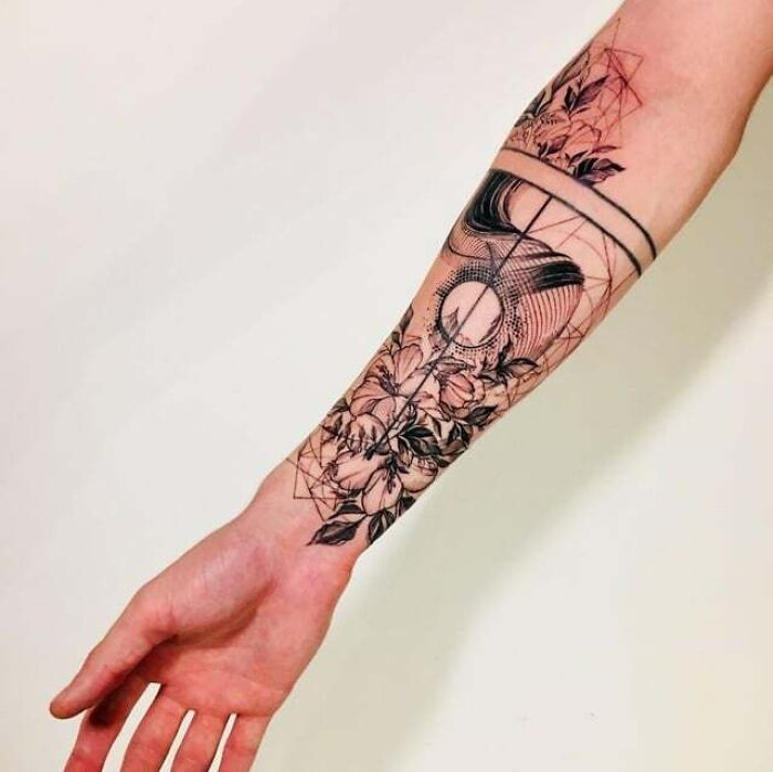 Abstract tattoo with geometric and floral elements on a forearm, showcasing artistry and self-expression.