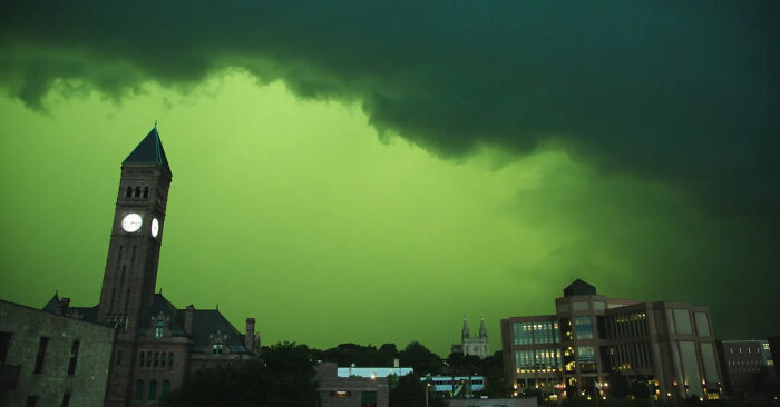 Dark green sky over a cityscape with ominous clouds, showcasing one of the weirdest pics from an online group collection.