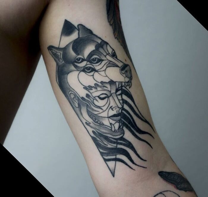 Abstract tattoo design featuring overlapping faces and a stylized wolf head on an arm.