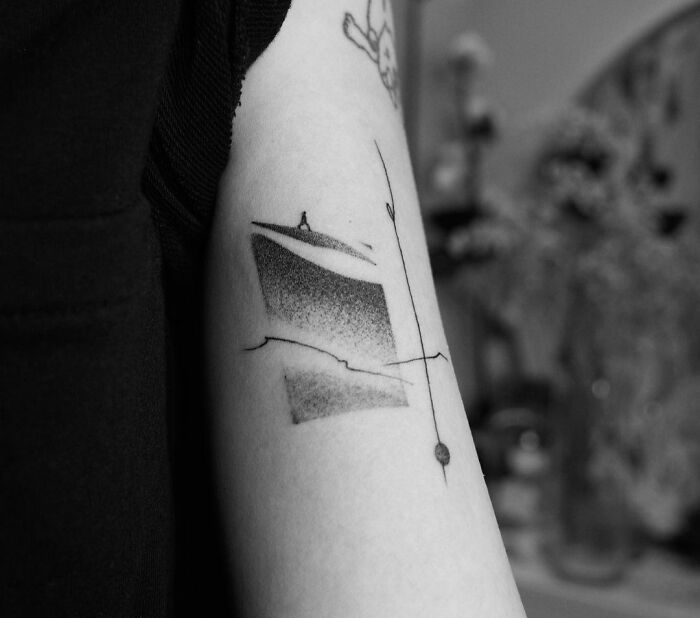 Abstract tattoo on arm, featuring geometric shapes and lines for self-expression.