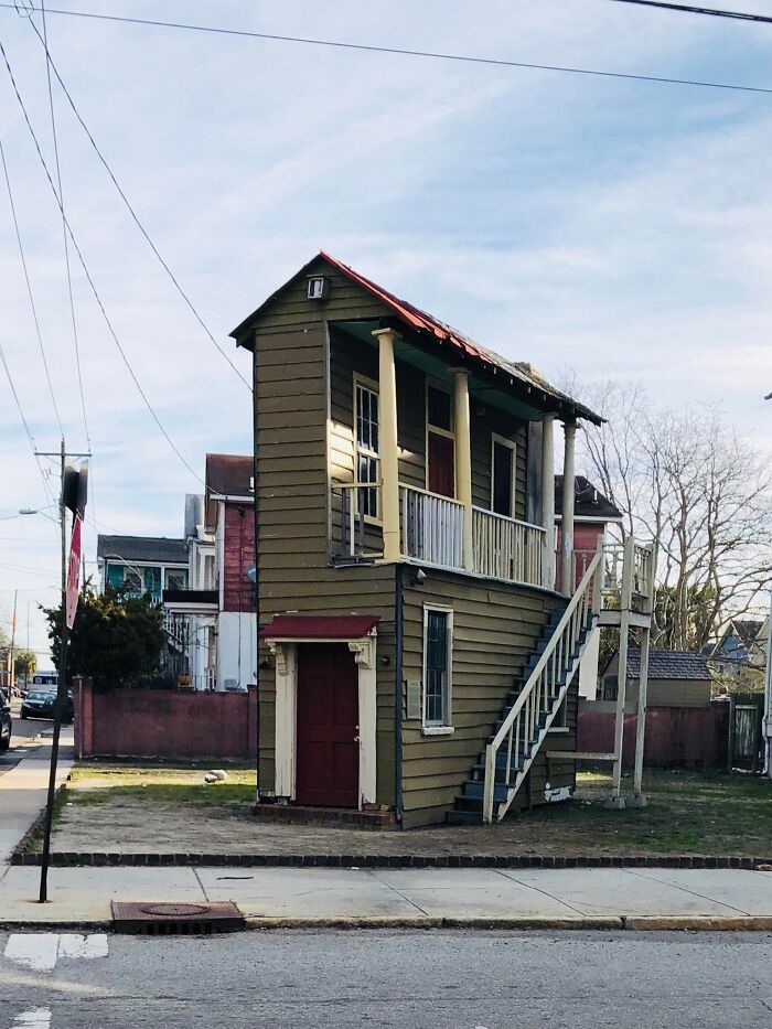 A strangely narrow two-story house with a staircase on the outside in a residential neighborhood, weirdest pics.