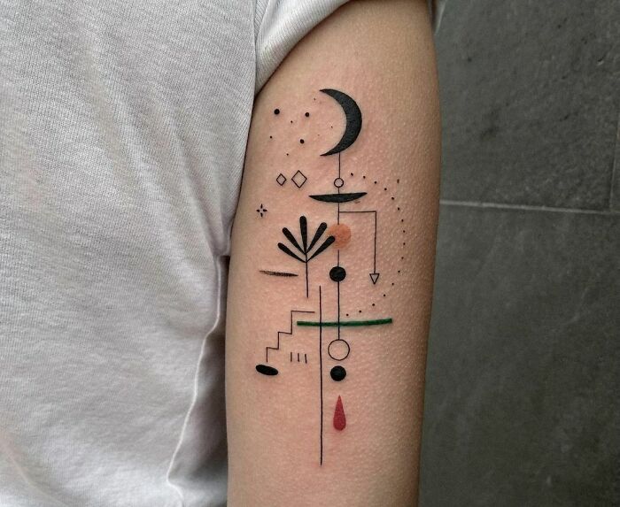 Abstract tattoo design on arm featuring geometric shapes and symbols in black and red ink.