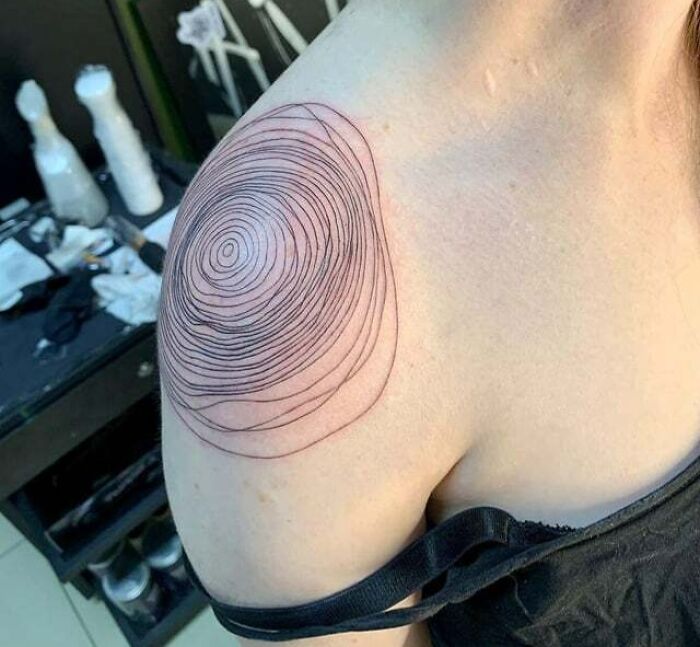 Abstract tattoo on shoulder featuring concentric circles, showcasing artistry and self-expression in body art.