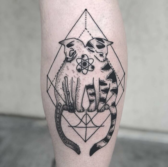 Two cats with an atomic symbol tattoo, blending art and science.