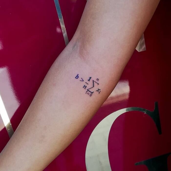 Math equation tattoo on forearm, symbolizing science passion.