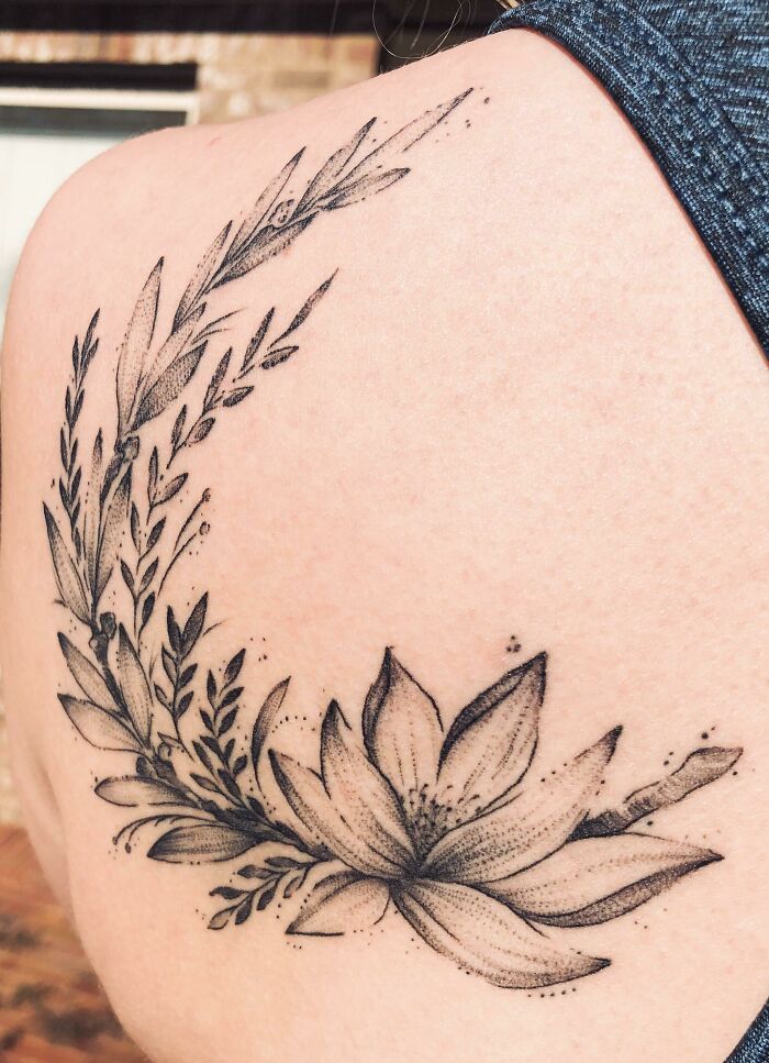 Floral mental health tattoo on shoulder with delicate leaves and lotus design.