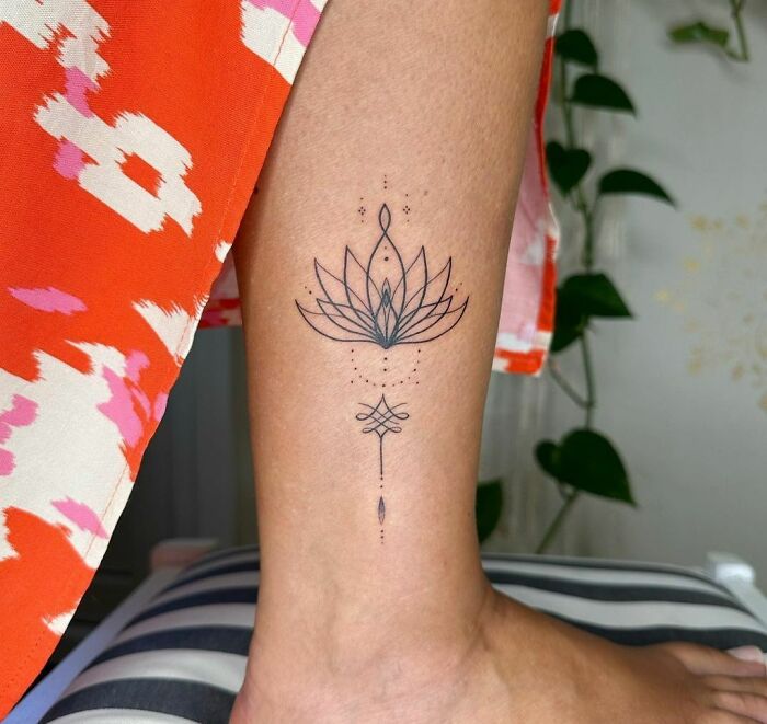 Elegant lotus tattoo on ankle, symbolizing powerful mental health and healing, against a colorful background.