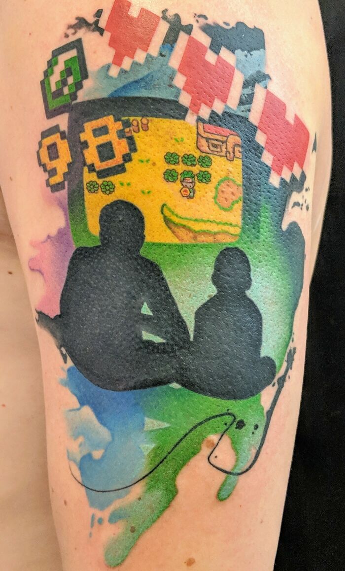 Tattoo of a family silhouette with video game elements, honoring family with creative design.