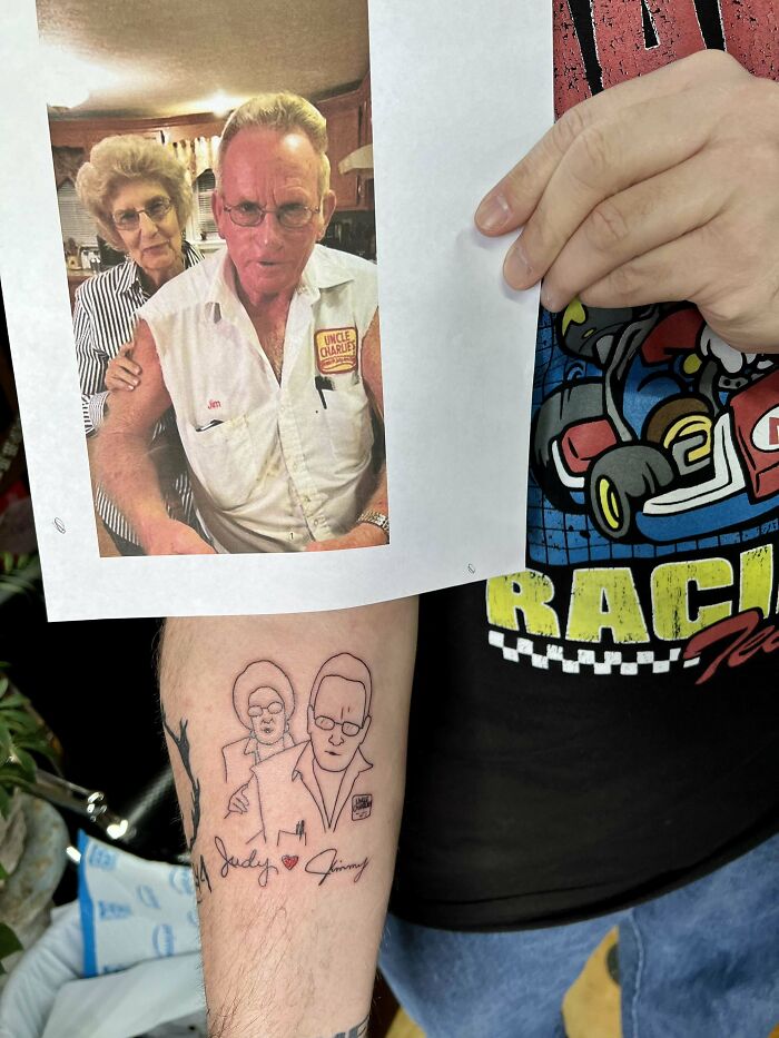 Family memorial tattoo featuring two figures and signatures on an arm, inspired by a printed photograph.