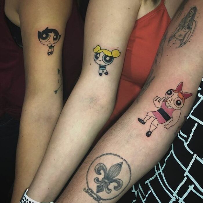 Cartoon tattoos on arms, showcasing permanent inked designs people willingly chose.