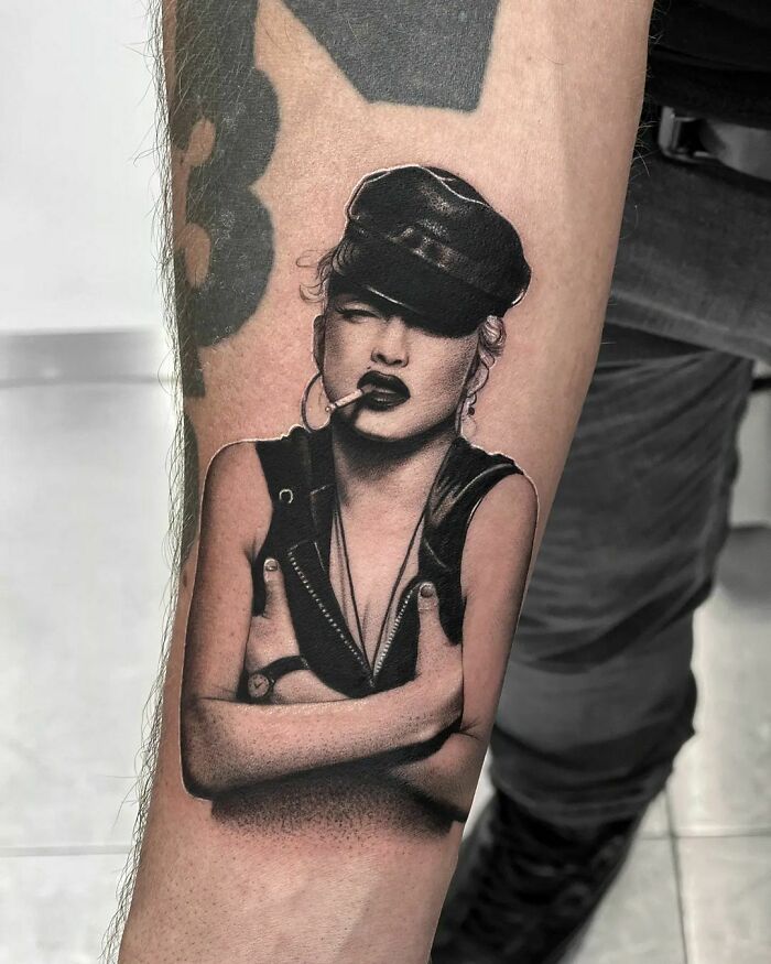 Realistic music tattoo of a woman in a leather hat and vest on a person's arm.