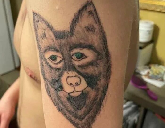 Tattoo of a wolf's face on upper arm, showcasing a common tattoo mistake.