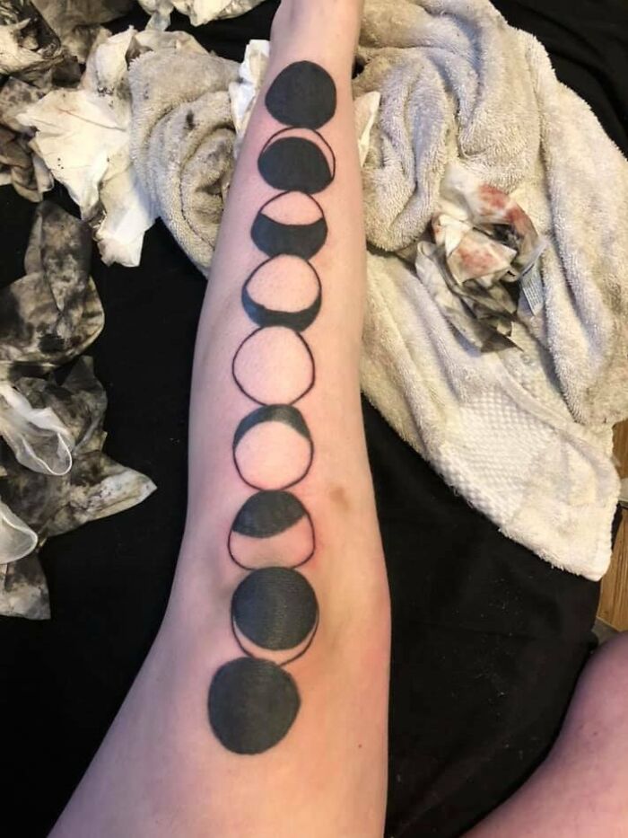 Arm with moon phase tattoo, indicating permanent ink mistake choice.