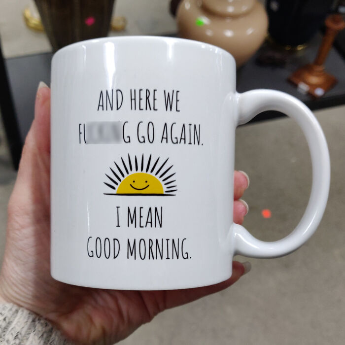 Hand holding a white mug with a funny morning quote and a smiling sun, showcasing creative mug life design.