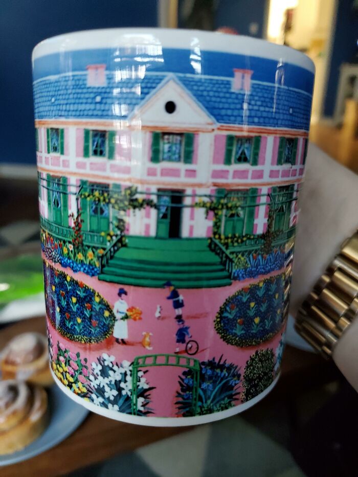 Colorful mug featuring a detailed house and garden scene with people, showcasing unique mug life design and art.