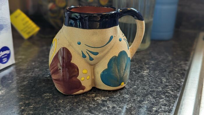 Decorative ceramic mug with painted floral patterns and a unique shape on a kitchen countertop, showcasing mug life creativity.