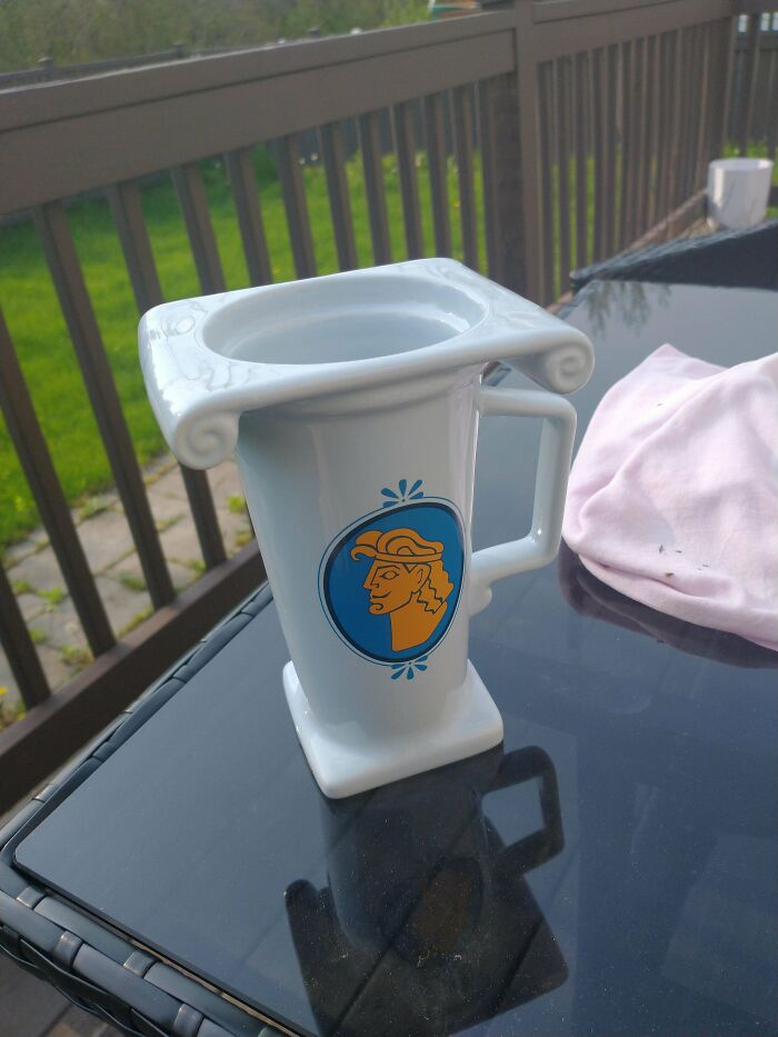 Unique ceramic mug with artistic design placed on outdoor glass table, showcasing creative mug life beyond usual use.