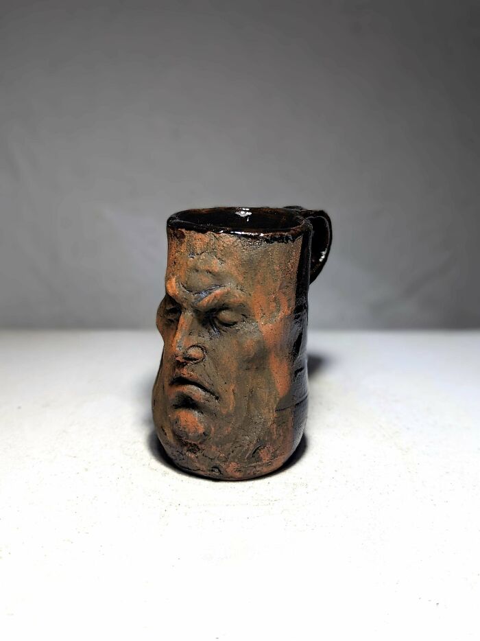 Ceramic mug featuring a detailed sculpted face with a stern expression, showcasing unique mug life design.