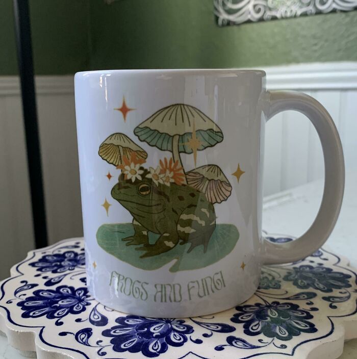 Ceramic mug featuring a frog and fungi design with flowers, highlighting creative and awesome mugs in everyday use.