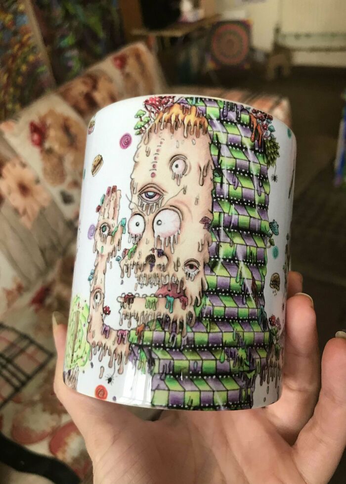 Hand holding a colorful mug with surreal melting face and patterned design, showcasing unique mug life art.