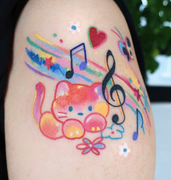 Colorful music tattoo featuring a cute cat with musical notes, stars, and hearts on skin.