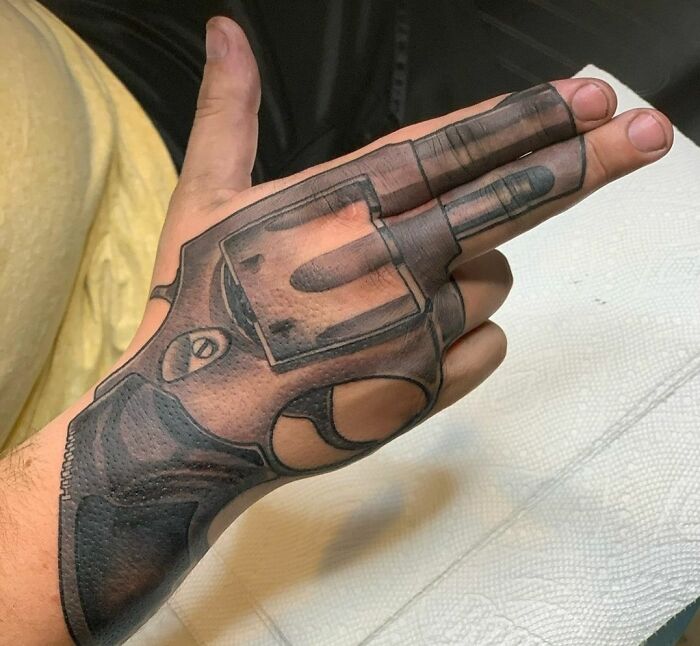 Revolver-shaped tattoo on a person's hand, illustrating tattoos that might not be well thought through.