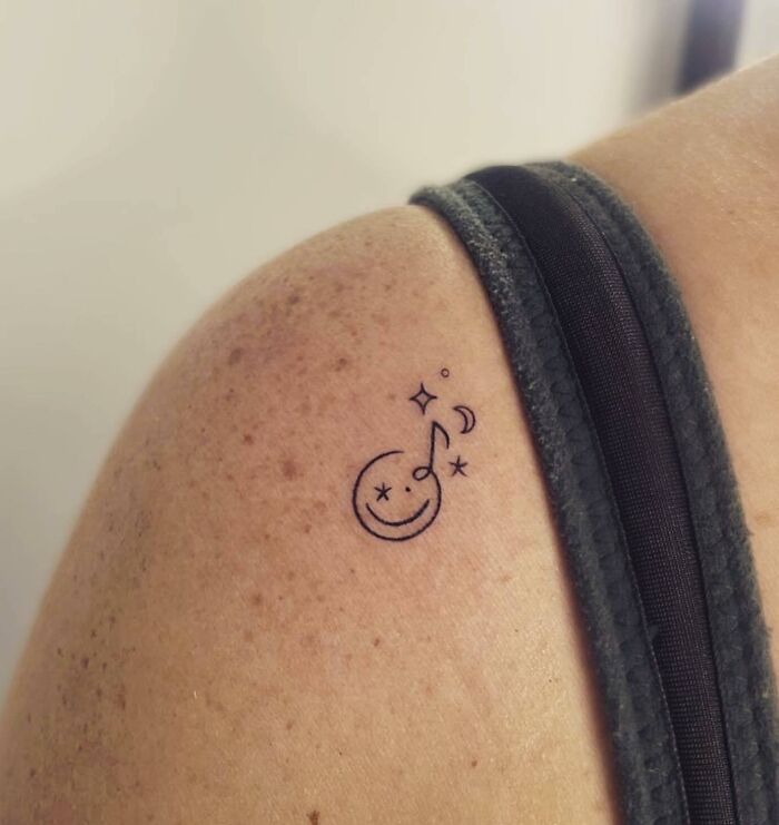 Minimalist music tattoo with a note and stars on shoulder.