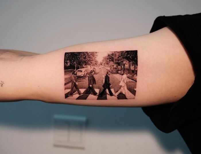 Music tattoo featuring iconic crosswalk scene inked on inner arm.