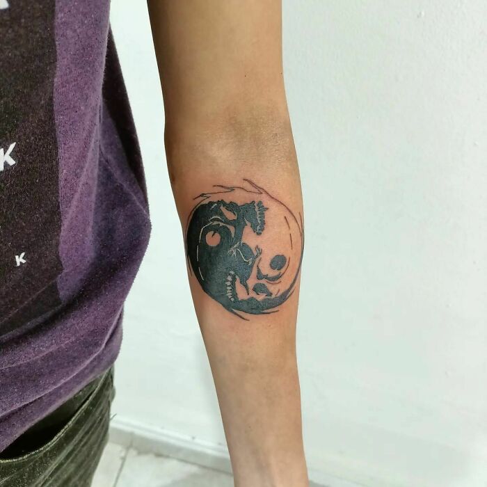 Black and white yin yang tattoo on forearm, symbolizing duality and balance.