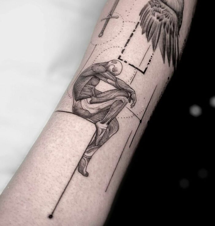 Abstract science tattoo on arm, featuring geometric shapes and anatomical figure design.