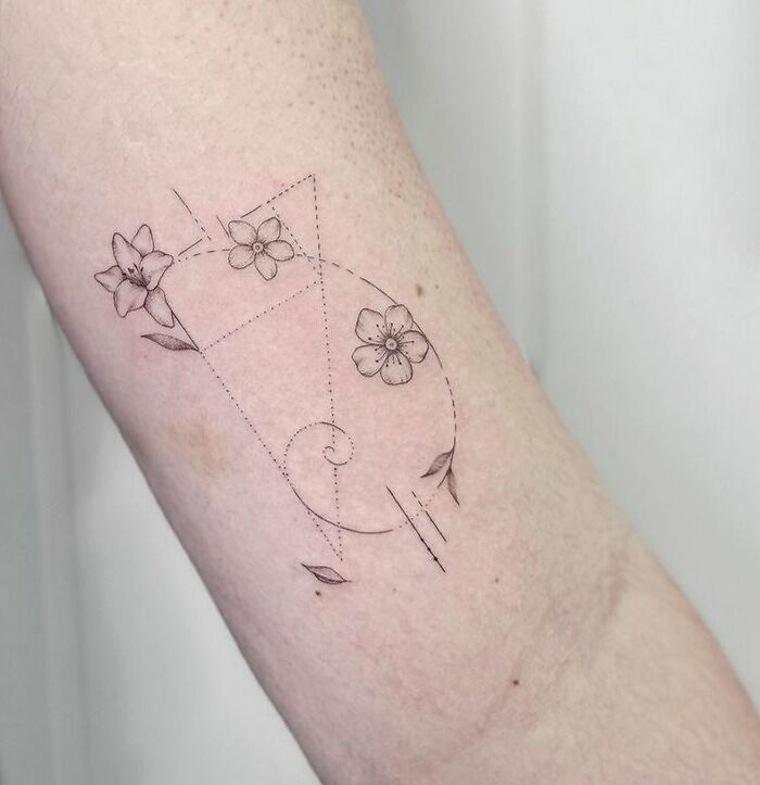 Delicate science tattoo featuring geometric shapes and flowers on forearm.