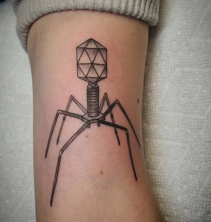 Science tattoo of a bacteriophage design on a forearm.