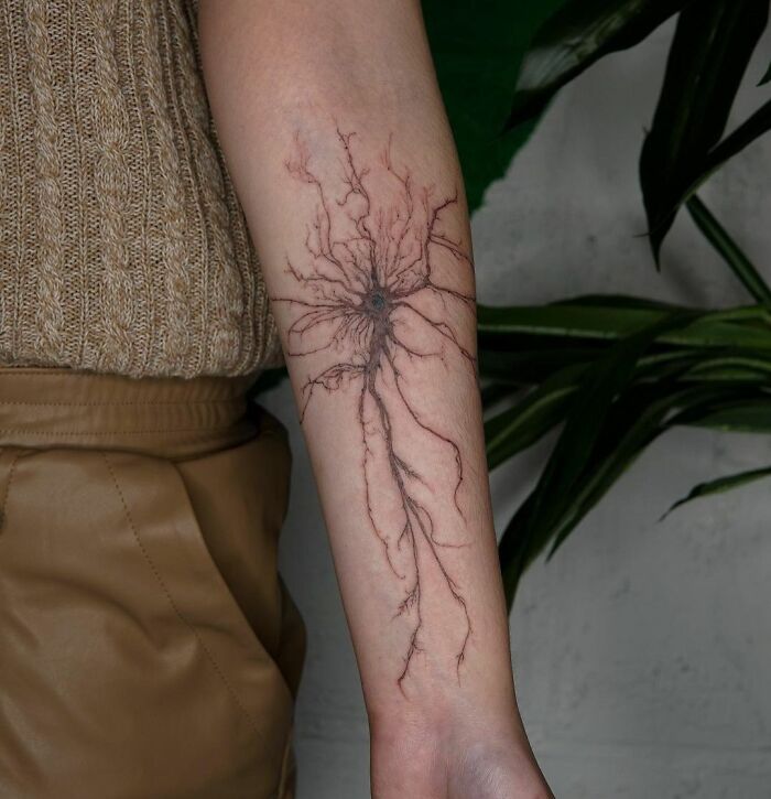 Science tattoo of a neuron design on forearm, depicting intricate nerve cell structure, for science enthusiasts.