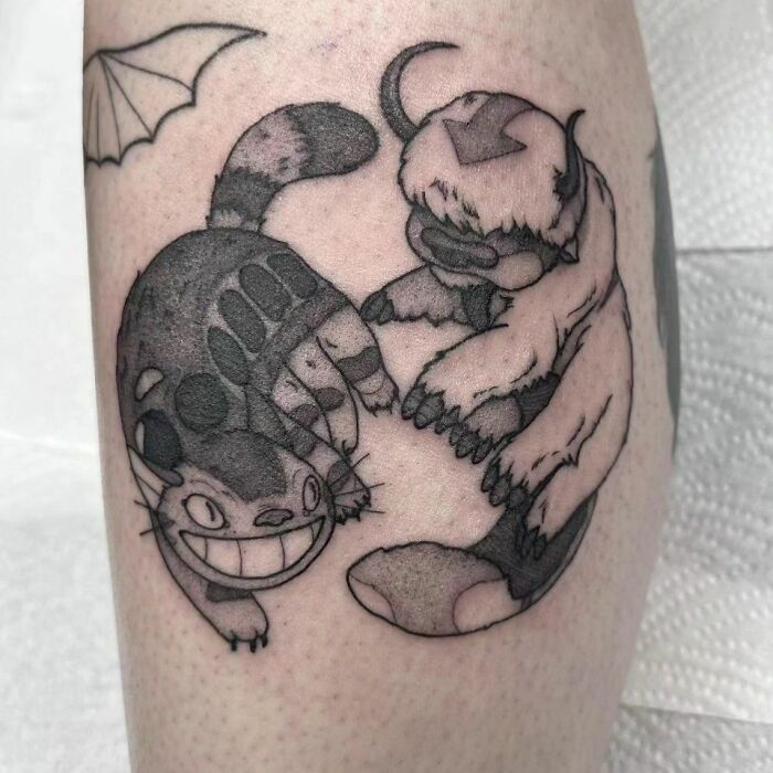Yin Yang tattoo featuring two animated creatures in a circular, balanced design on skin.
