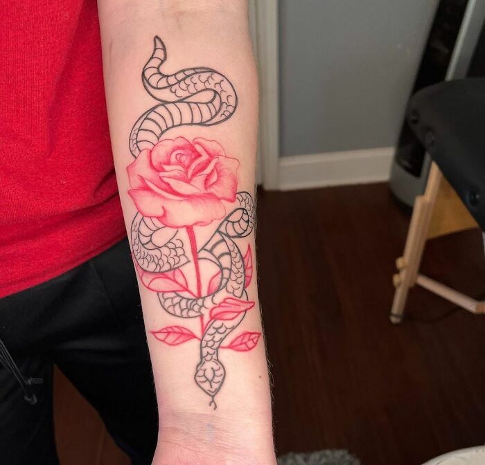 Snake tattoo entwined with a vibrant red rose on forearm.