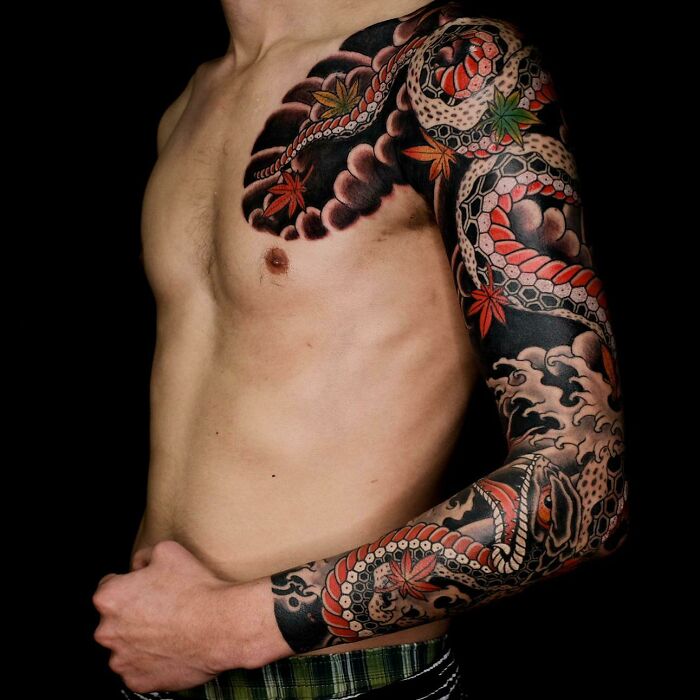 Man with detailed snake tattoo covering arm and shoulder, featuring vibrant colors and intricate patterns.